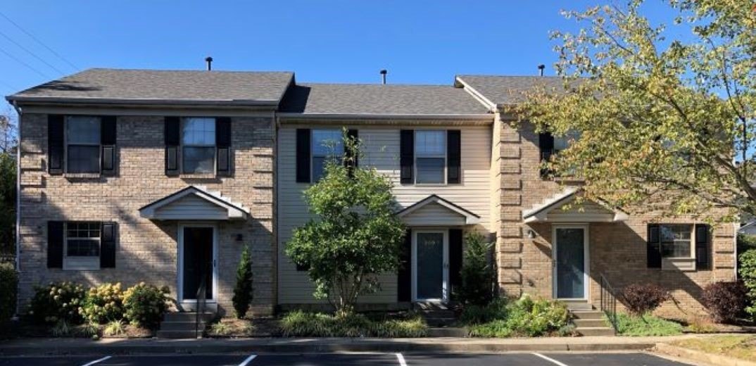 A row of Kirkwood Village townhomes with brick and siding facades, covered entries, and mature landscaping.
